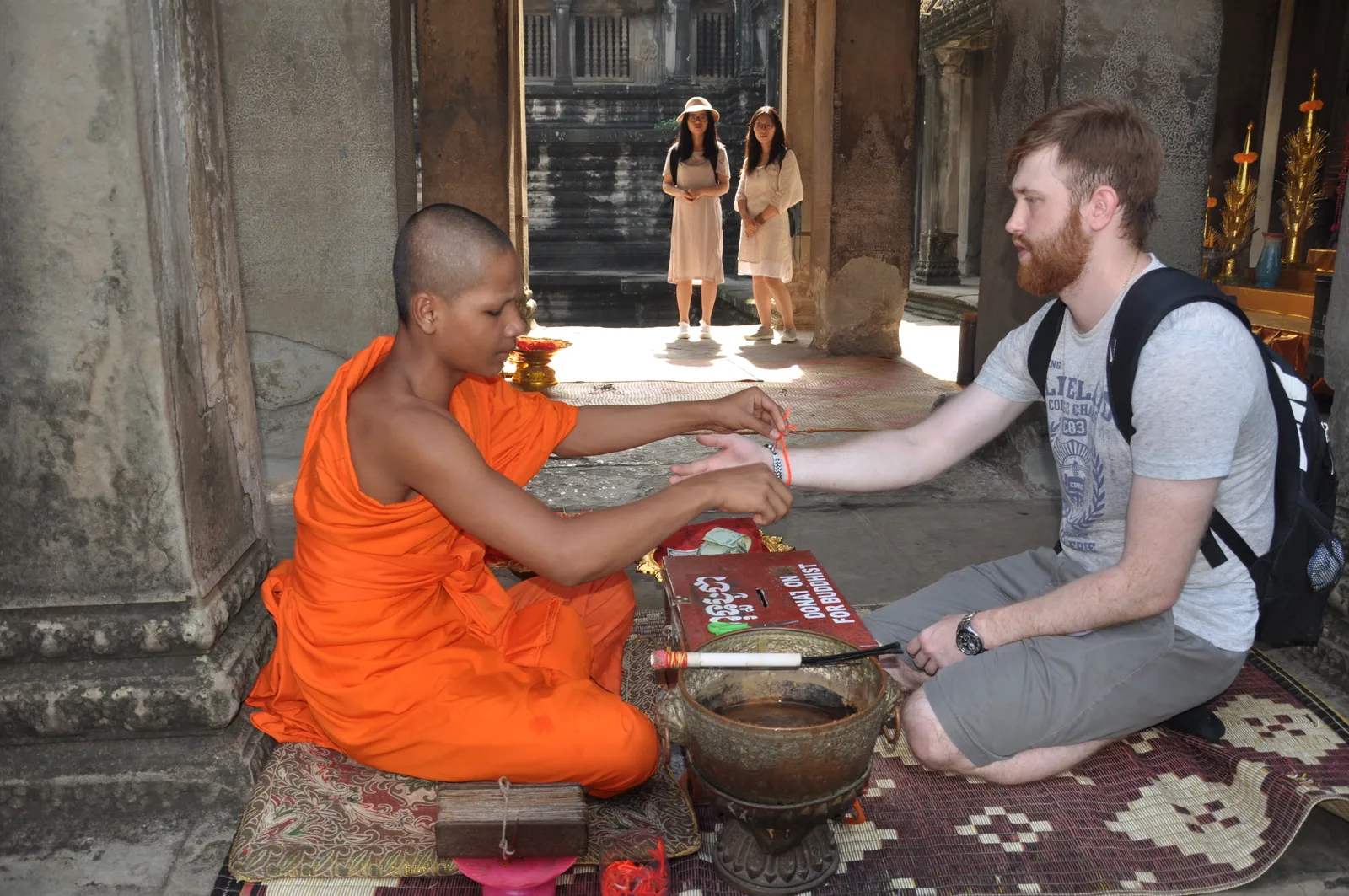 A monk's hands tying a white Sai Sin blessing thread